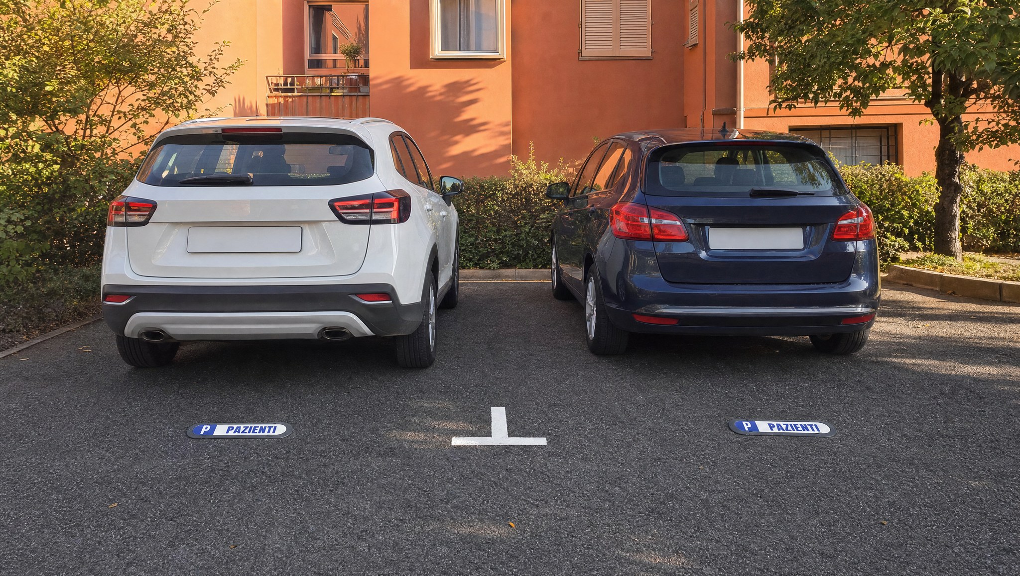 Deux voitures garées devant deux plaques Com’Park PAZIENTI sur le parking d’un cabinet médical à Bologne